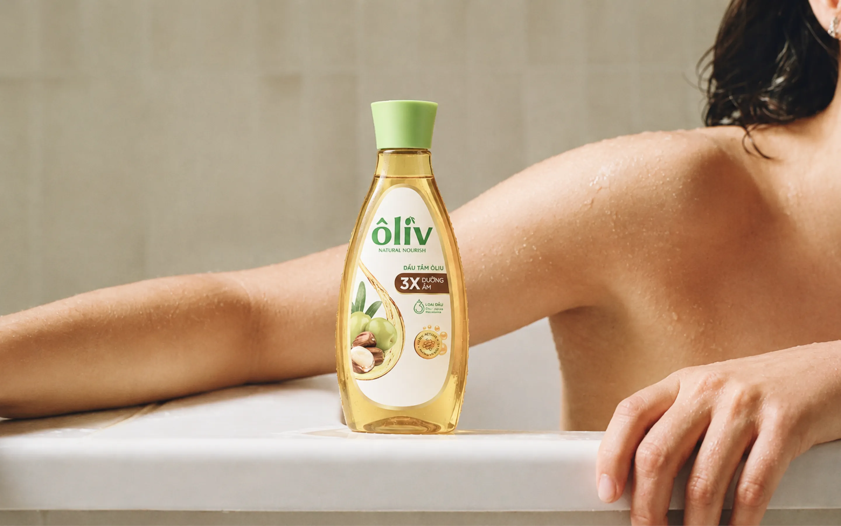 Oliv shower oil bottle on the edge of a bathtub